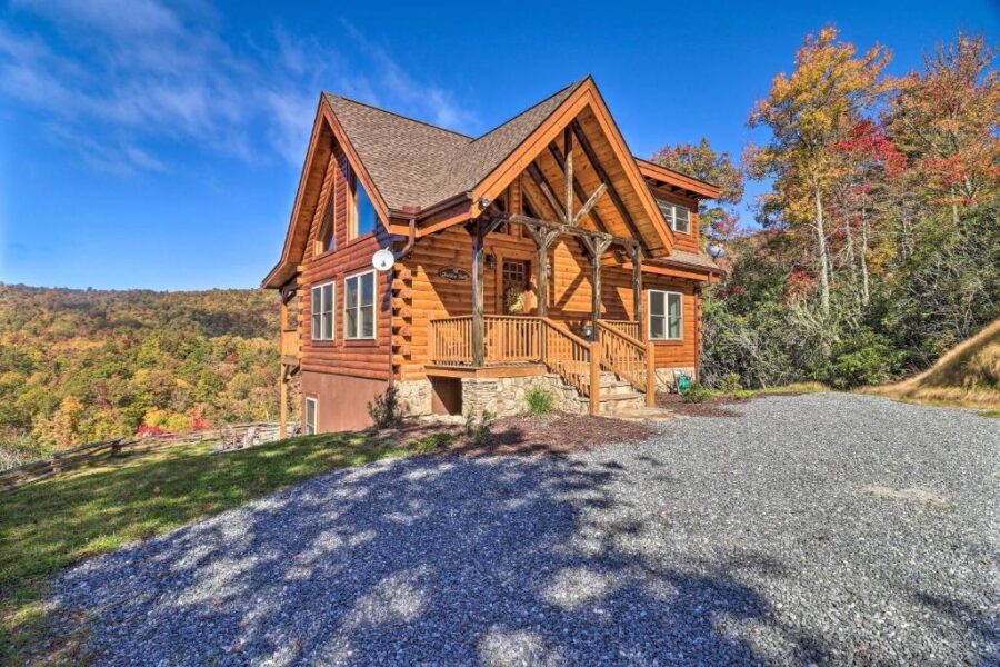 Hilltop log cabin with a large gravel driveway and parking area, featuring a hot tub and waterfall on 5 acres in Gatlinburg.