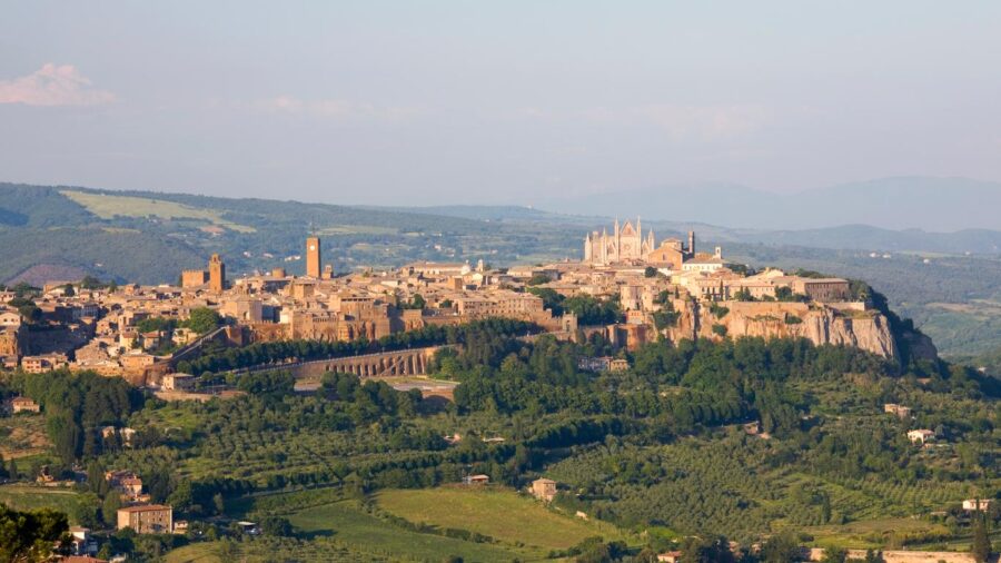 Aerial view of historic Orvieto hilltop town amidst lush green landscape.