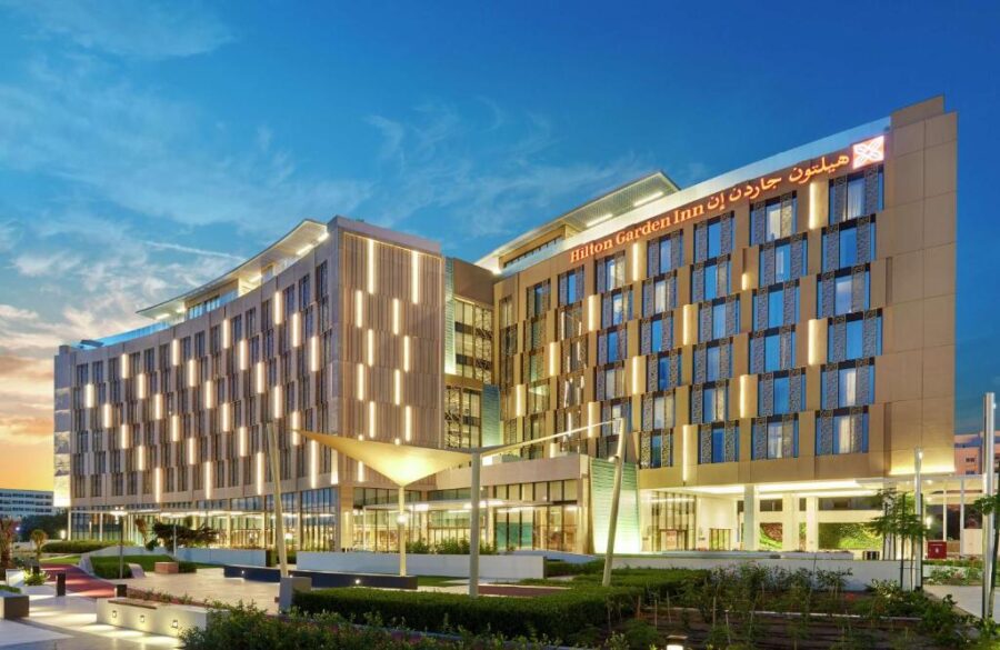 Hilton Garden Inn Muscat Al Khuwair hotel exterior at dusk with modern architecture and lighting.