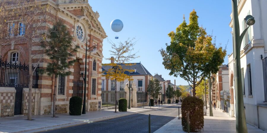 Historic Avenue de Champagne cobblestone street with brick buildings, autumn trees, and tethered balloon.