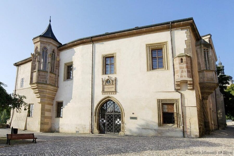 Hrádek Silver Mine museum historic facade with stone turrets, oriel, and cobbled forecourt.