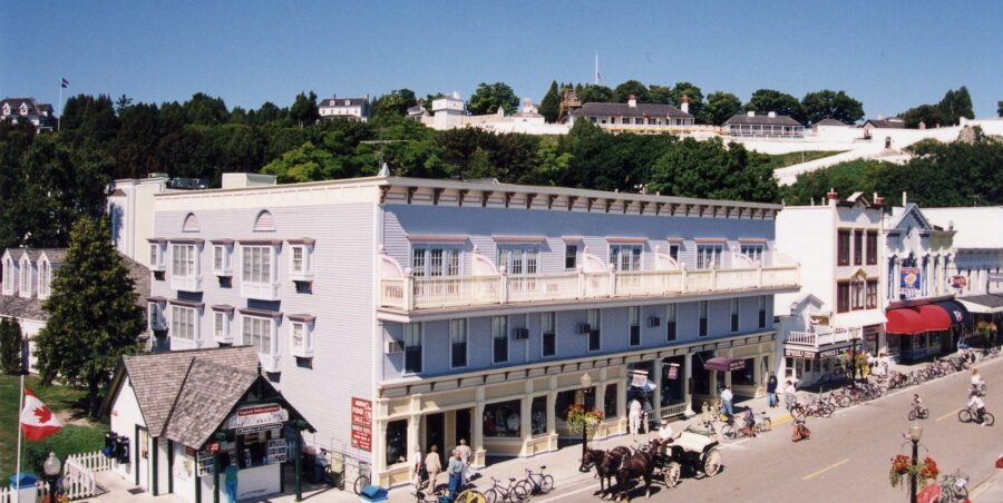 Summer main street with Murray Hotel, horse-drawn carriage, bicycles, pedestrians in historic Canadian town.