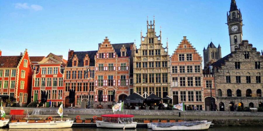 Graslei historic canal quay with colorful medieval townhouses and moored boats.