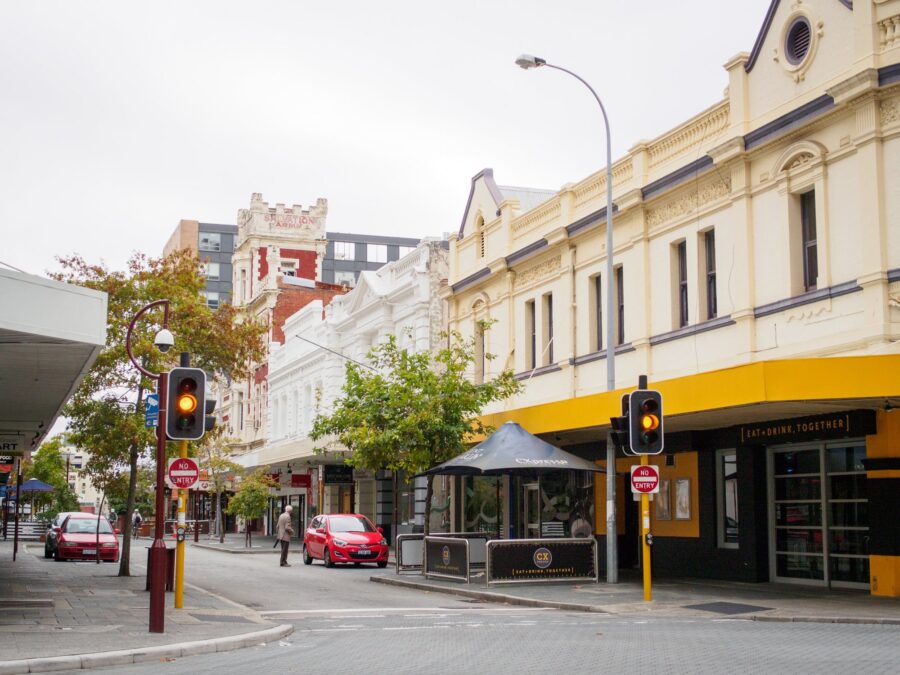 Historic Northbridge city street with heritage buildings, café corner, traffic lights and parked cars.