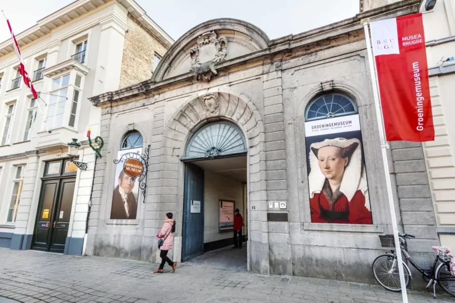 Groeninge Museum Bruges entrance with historic stone facade and portrait posters.