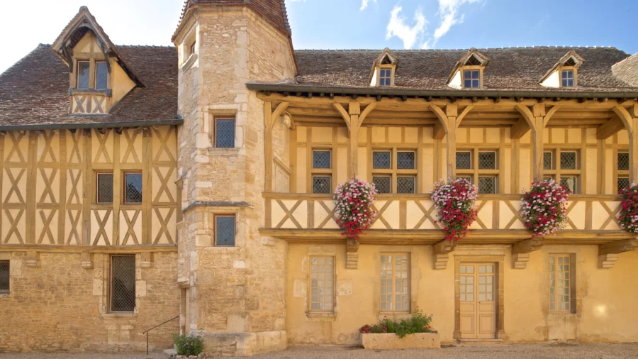 Burgundy wine museum: historic ochre half-timbered house with stone turret and flowers.