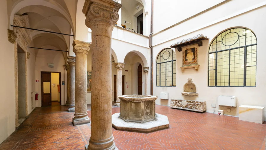 Pinacoteca Nazionale courtyard with central stone well, arched columns, and terracotta floor.