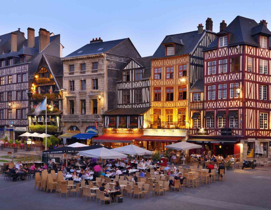 Rouen historic timbered square in France with evening cafes and outdoor dining.