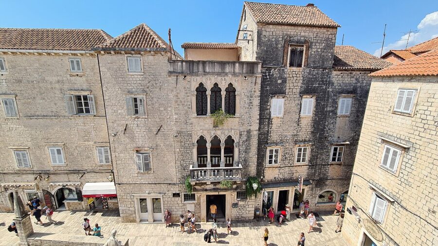 Bustling historical town plaza with diverse crowds and stunning architectural heritage.