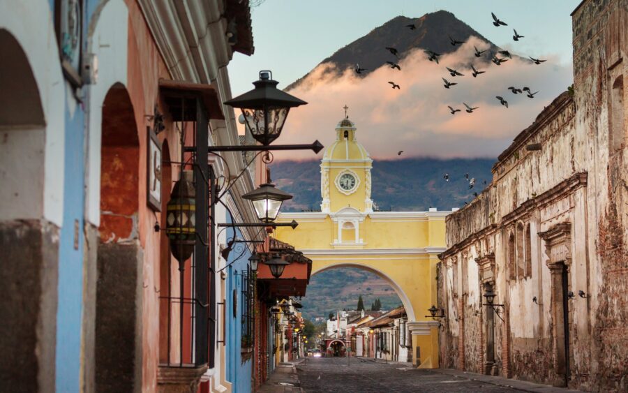 Antigua Guatemala street with Arco de Santa Catalina and Volcán de Agua in the backdrop.