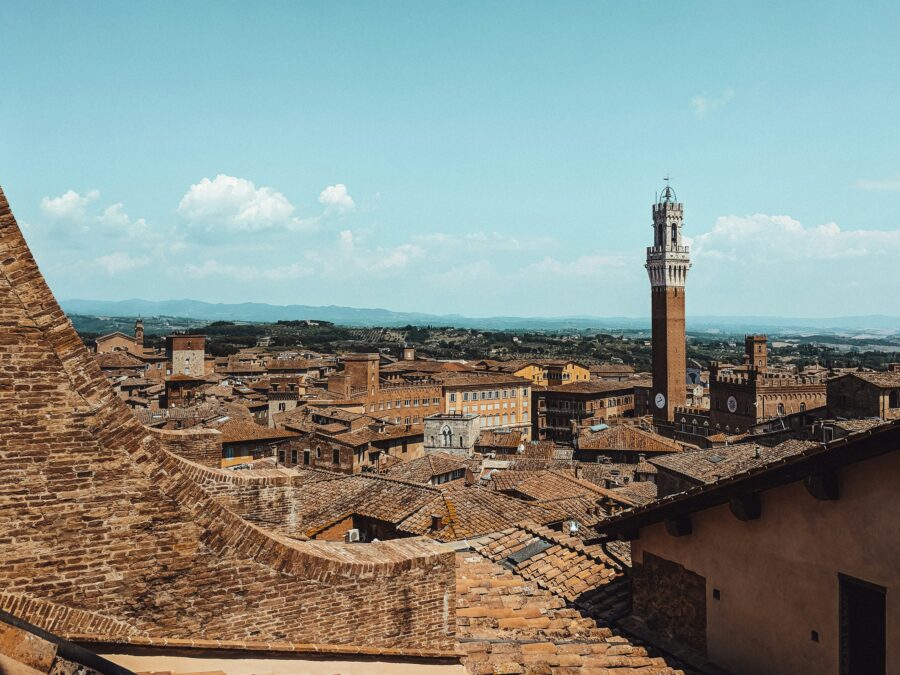 Siena Italy skyline with medieval tower and terracotta rooftops.
