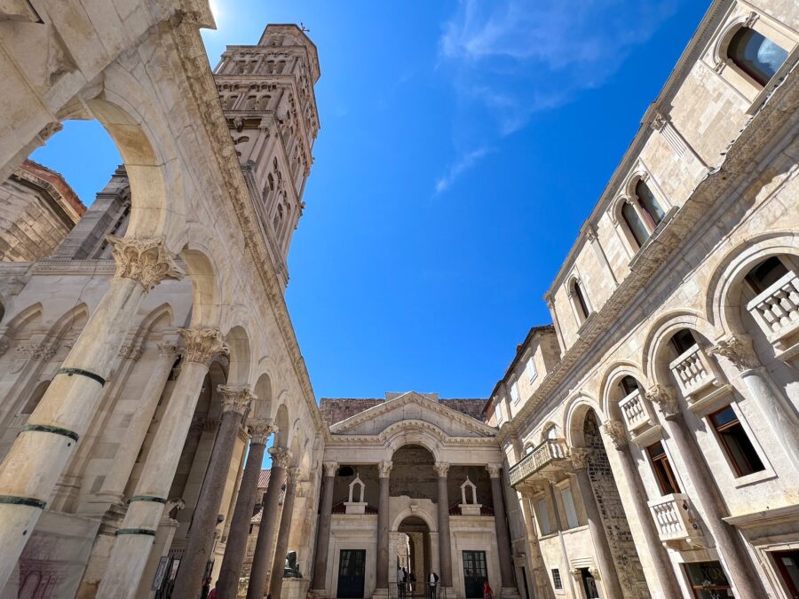Grand Romanesque bell tower with arches and columns against a vibrant blue sky.