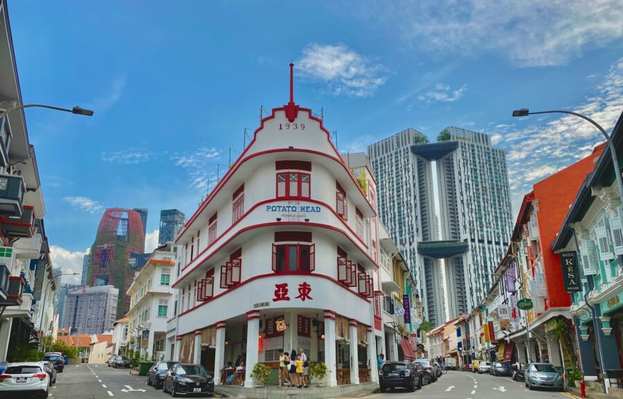 Urban Chinatown streetscape blending historic architecture with modern skyscrapers, featuring POTATO HEAD building.