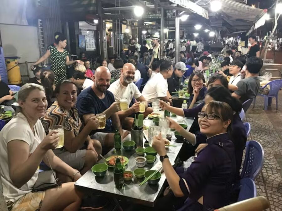 Group of people enjoying drinks at tables during a night food tour in Ho Chi Minh City with a local host.