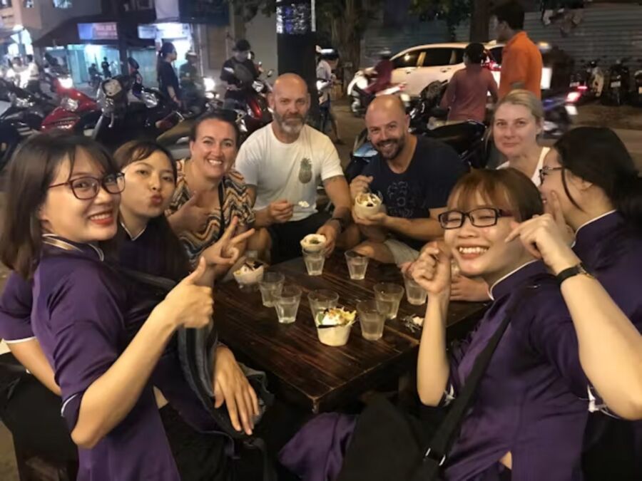 Diners gathered around a table filled with food, experiencing a night scooter food tour in Ho Chi Minh City.