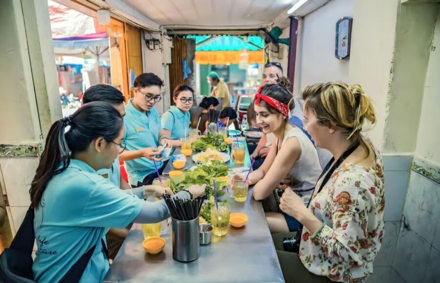 Participants seated at a table with drinks, sharing experiences on the Ho Chi Minh Food Tasting and Sightseeing Tour.
