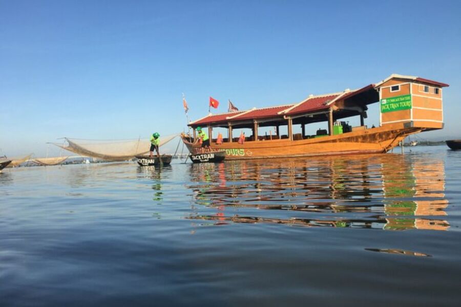 Boat featuring a canopy, floating on the river during a picturesque sunset in Hoi An.

