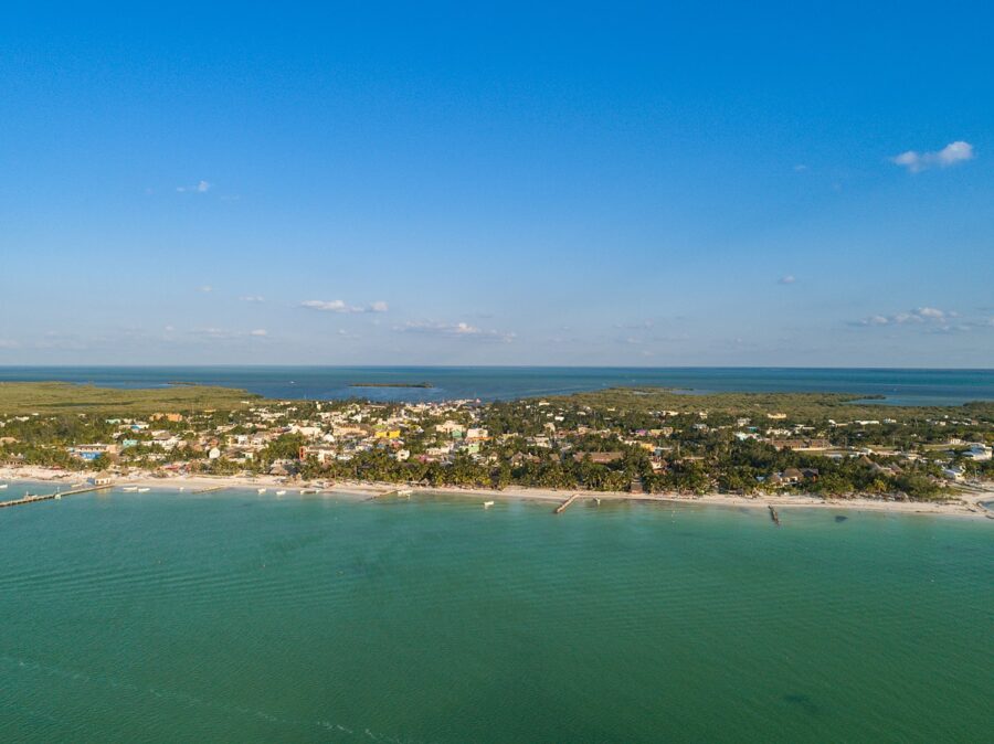 Aerial view of Holbox Island town and beach in Mexico, showcasing sandy shores and colorful buildings.
