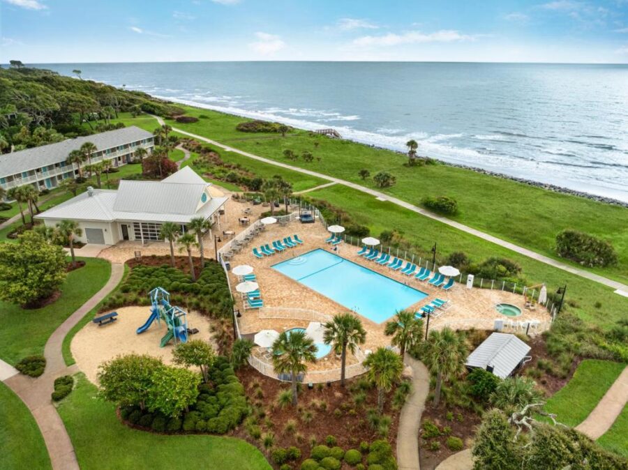 Aerial view of Holiday Inn Resort Jekyll Island, showcasing the hotel, pool, and surrounding lush greenery and beach.

