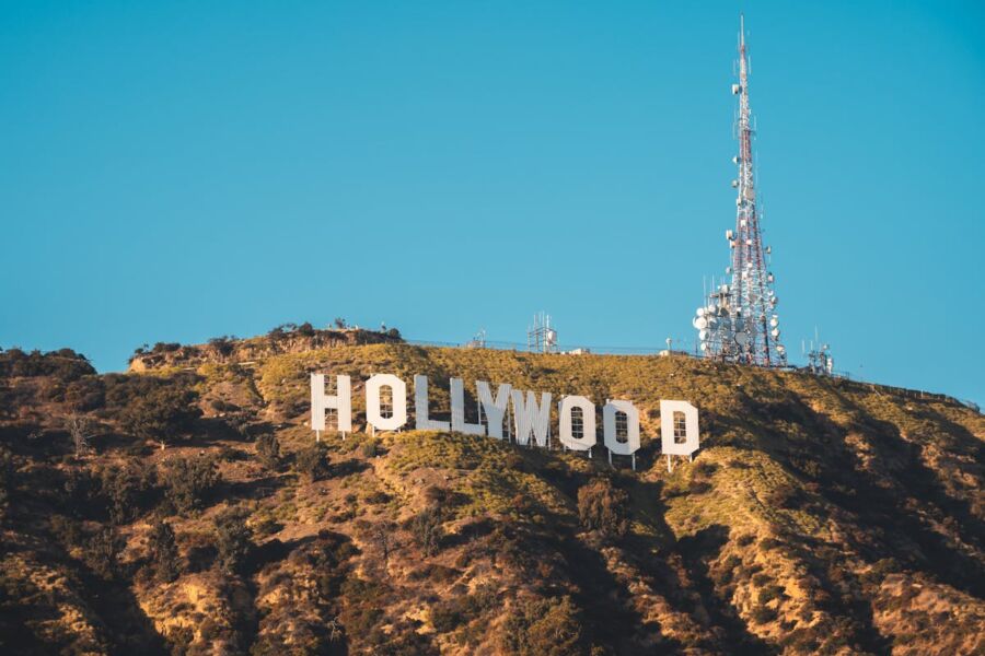 Iconic Hollywood Sign with communication tower under clear blue skies in lush Los Angeles.