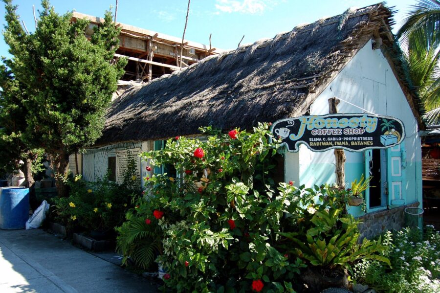 Honesty coffee shop in Batanes: thatched cottage with turquoise trim and hibiscus.