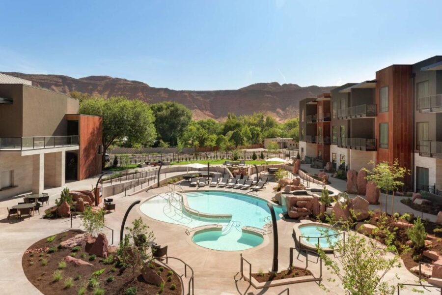 The inviting pool area at Hoodoo Moab, Curio Collection by Hilton, with stunning mountain scenery in the background.