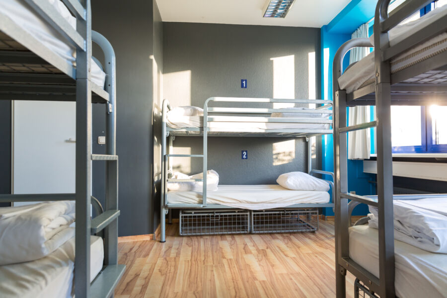 Interior of a hostel featuring metal bunk beds with neatly arranged linen