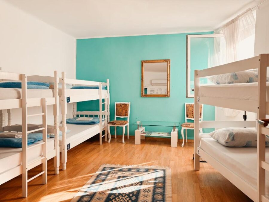 Interior of Hostel Miran Mostar showcasing bunk beds and a calming blue wall, ideal for travelers.
