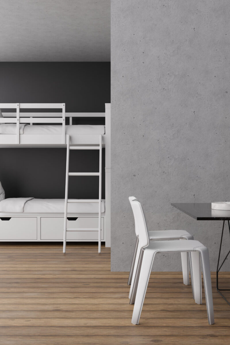 Interior of a hostel featuring bunk beds, a simple dining table, and wooden flooring in a sleek, minimalist design.