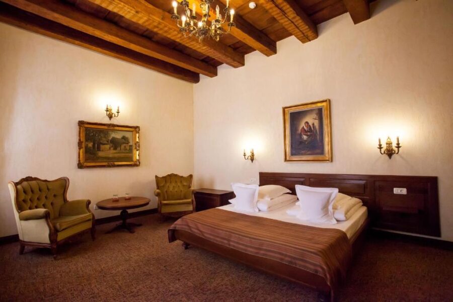 Elegant baroque-style beds in a well-decorated room at Hotel Bella Muzica, showcasing luxury and comfort.