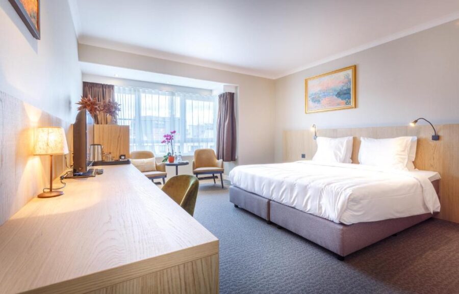 Hotel Carlton room in Ghent featuring a bed, desk, and chair, designed for comfort and relaxation.
