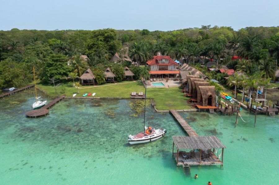 Aerial view of Hotel CasaBakal in Bacalar, featuring a dock and boats on the serene lagoon.
