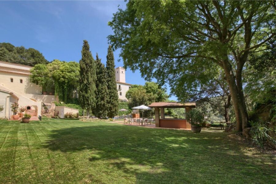 The expansive grounds of Hotel Convent de Begur, showcasing a variety of trees and a flourishing garden area.