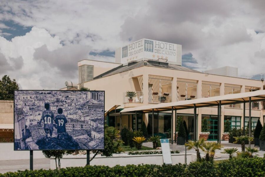 Exterior view of Hotel Del Campo in Matera, showcasing a blue sign on the building.