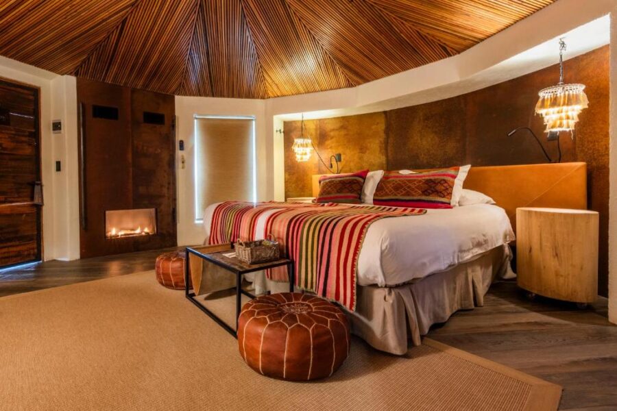 Interior of a hotel bedroom at Hotel Desertica, showcasing a wooden ceiling and a comfortable bed in San Pedro de Atacama.
