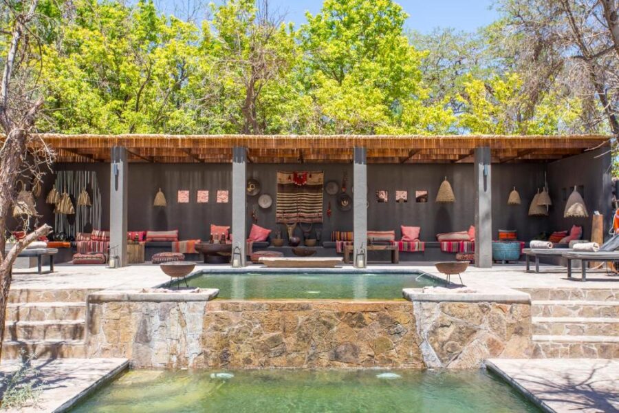 Pool area at Casa de Campo, Hotel Desertica, featuring lounge chairs and palm trees in San Pedro de Atacama, Chile.