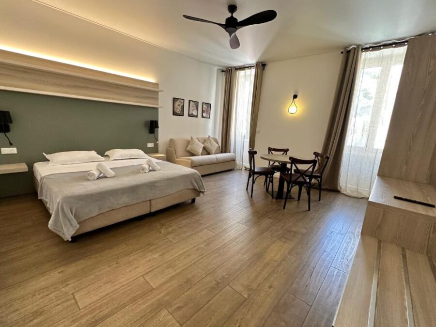 Bedroom at Hôtel du Nord, France, showcasing a bed, a television, and a ceiling fan for comfort.