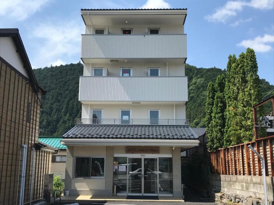 Modern Hotel Famitic Nikko exterior with balconies, mountain backdrop and parking area in Nikko.
