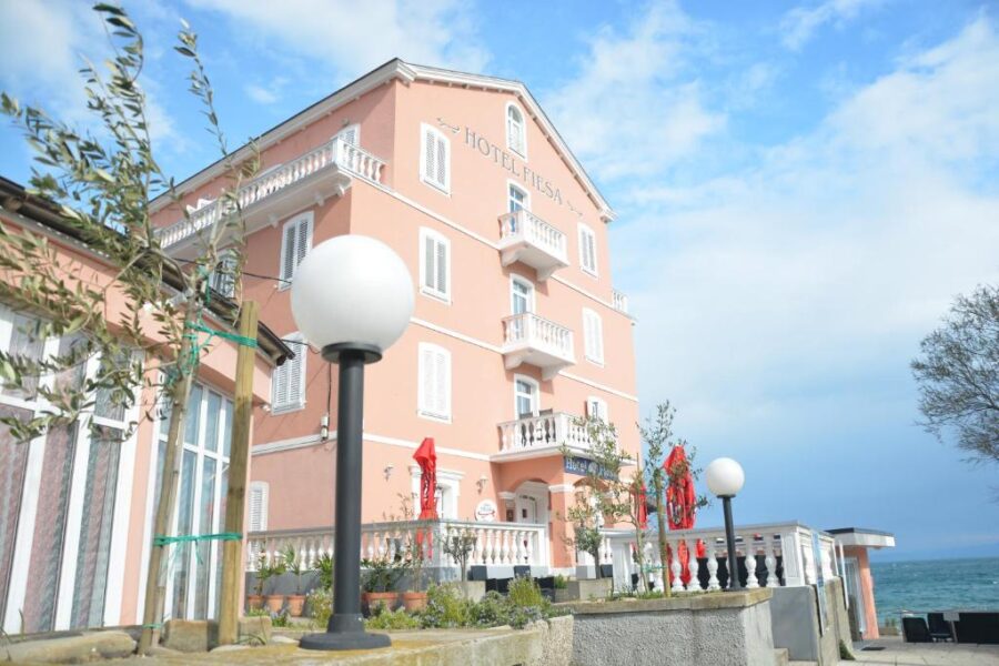 Hotel Fiesa, a pink building with white windows and a lamp, situated in Piran, Slovenia.