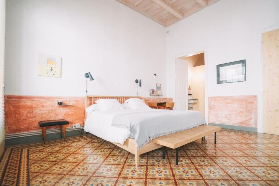 Hotel Hevresac Singular & Small in Menorca, showcasing a bedroom with a bed and warm orange walls.