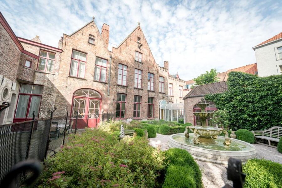 The courtyard of Hotel Jan Brito in Bruges, showcasing a central fountain and charming building facade.