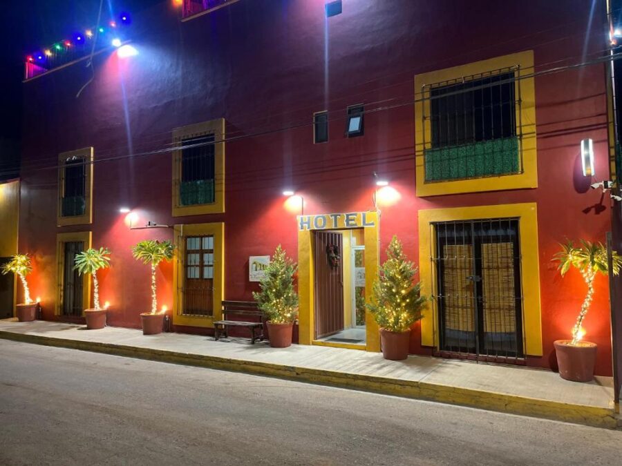 Colorful Hotel La Cascada in Oaxaca, Mexico, illuminated at night with bright lights shining from its windows.
