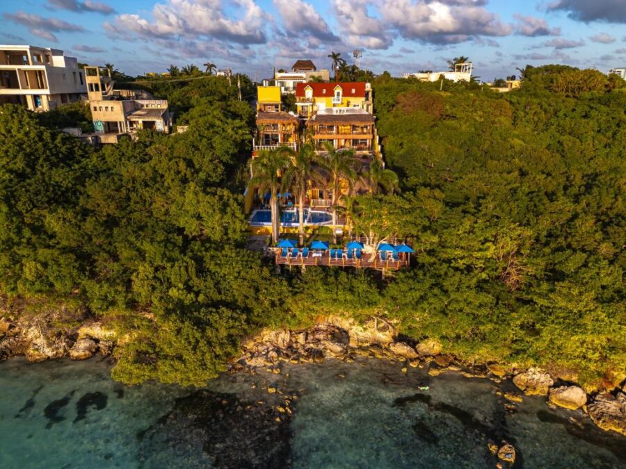 Aerial view of Hotel La Joya, a tropical resort on the beach in Isla Mujeres, surrounded by clear blue waters.
