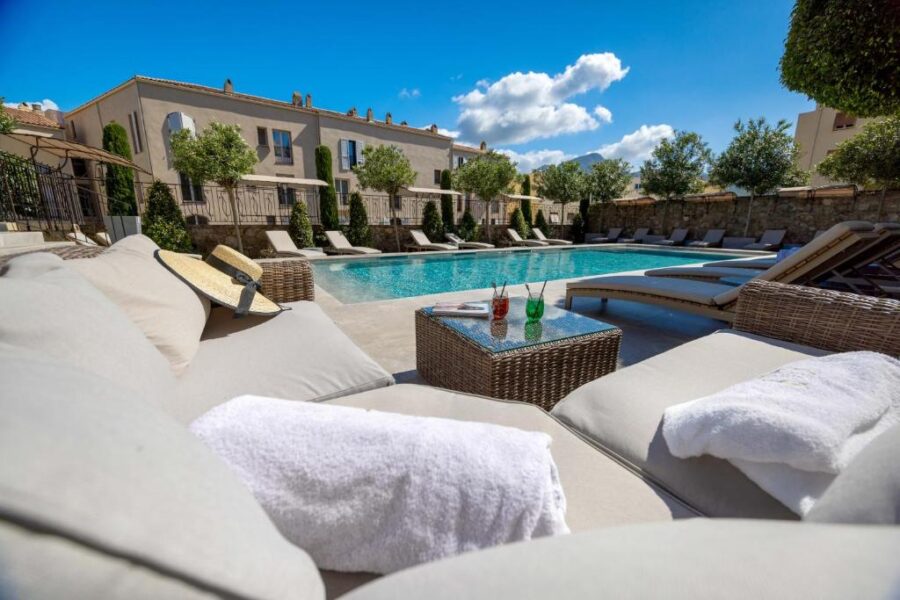 The pool area at Hôtel L'Abbaye, France, featuring lounge chairs and towels for guests to enjoy.