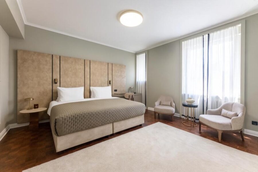 Interior of a hotel bedroom with a bed, chair, and window at Hotel Majestic in Belgrade, Serbia.
