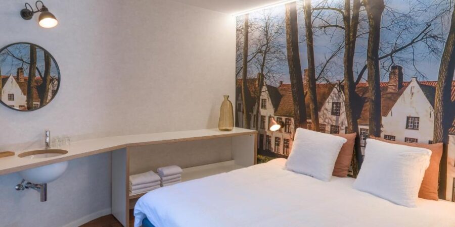 Hotel Marcel in Bruges: a cozy hotel room featuring a bed, sink, and a vibrant wall mural.