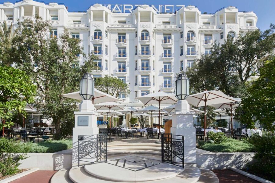 Luxurious Hotel Martinez facade with European design, balconies, gardens, and outdoor seating.