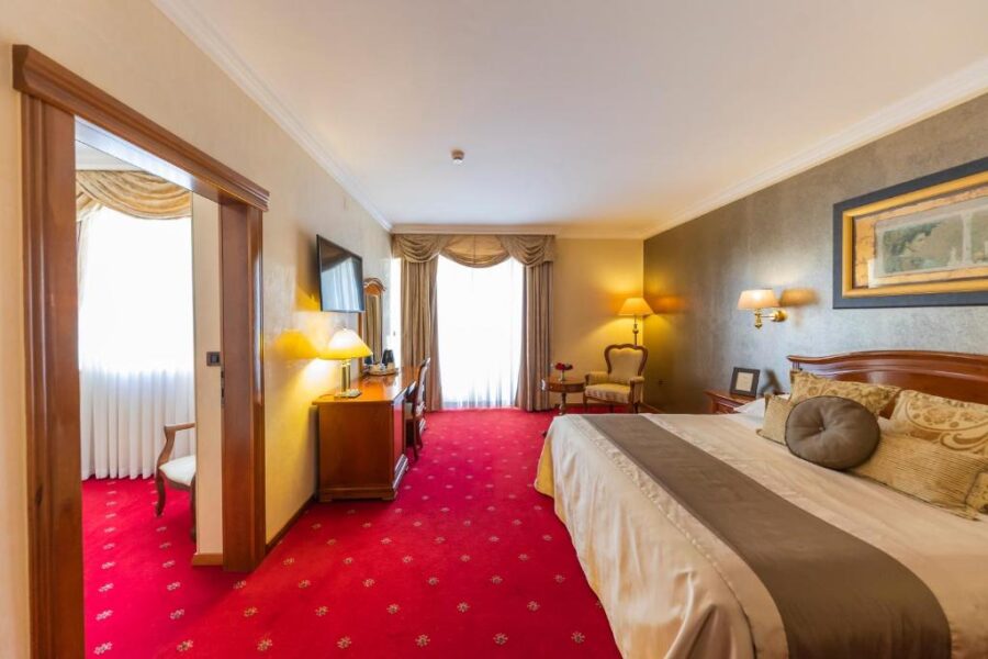 Interior of Hotel Niko in Zadar, Croatia, showcasing a cozy bed on a vibrant red carpet.