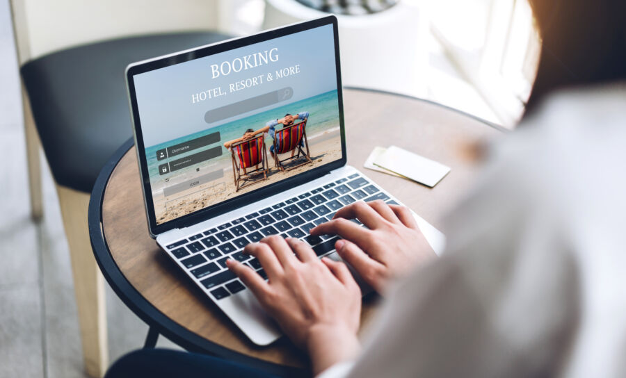 Woman using a laptop to book a hotel or resort online, focused on the screen in a cozy indoor setting