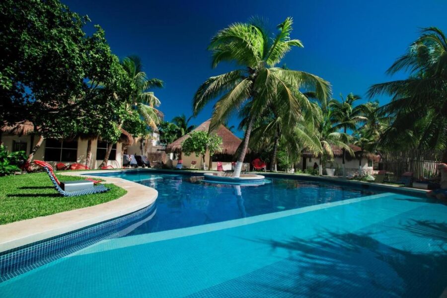 Hotel Paradise Suites features a tranquil pool encircled by palm trees and a charming house in Isla Mujeres, Mexico.
